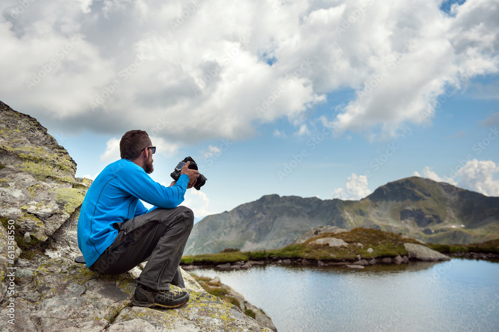 Young man portrait with camera outdoor in the mountains. Alps, I