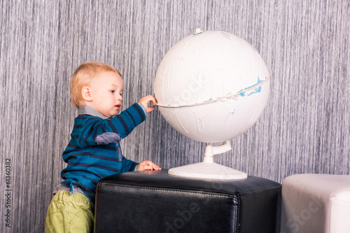 Adorable curious baby boy with a globe photo