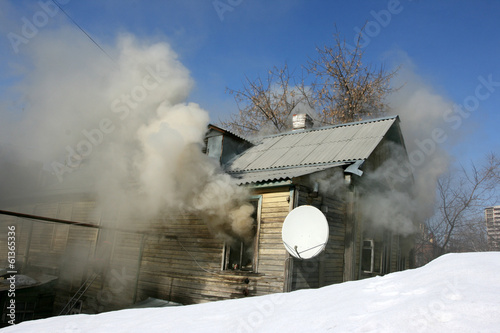 Private house in the fire puffs against a blue sky in the winter