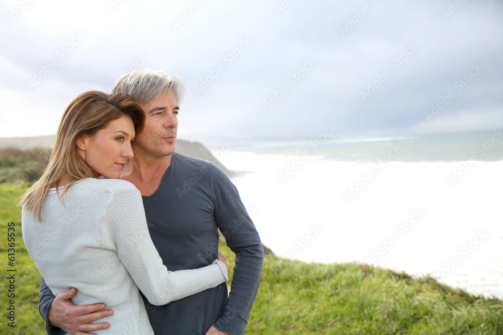 Cheerful middle-aged couple on the ocean coastline