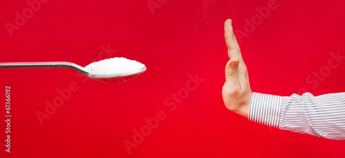 Saying no tu sugar suggested by a hand refusing a teaspoon