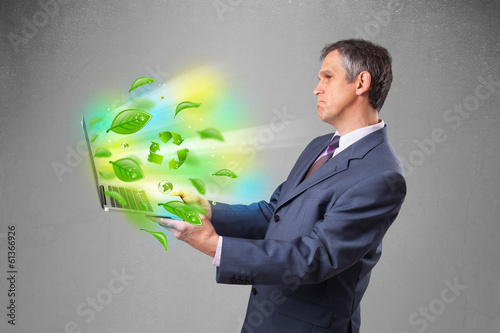 Businessman holding laptop with recycle and environmental symbo
