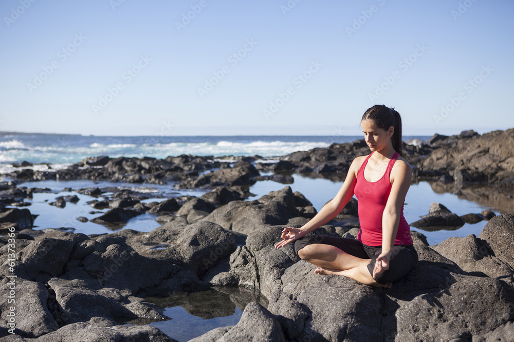 young woman practicing yoga meditation on the beach