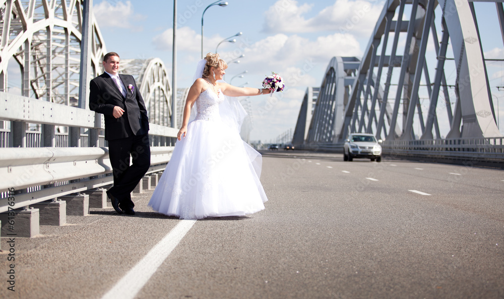 Obraz premium Newly married couple hitchhiking on road