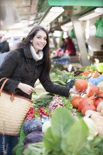 young woman choosing vegetables on a market photo