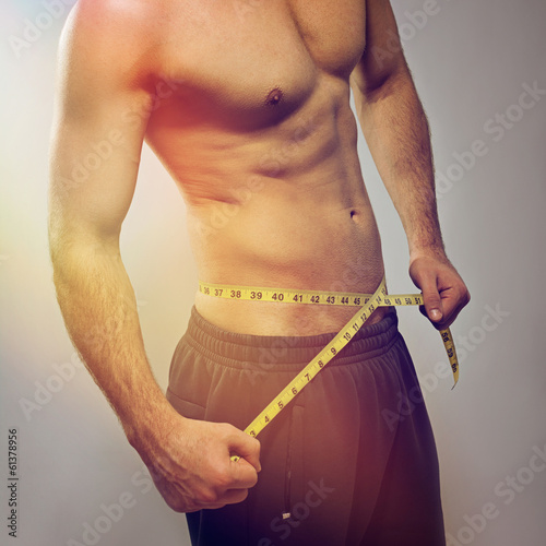 Fit young man measuring waist