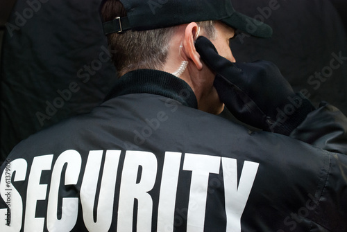 Fototapeta Security Guard Listens To Earpiece, Back of Jacket Showing
