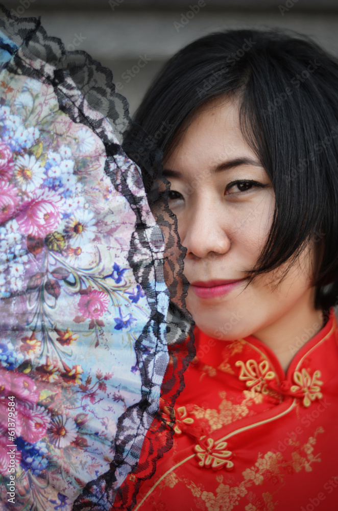 asian woman wearing a cheongsam with  folding fan