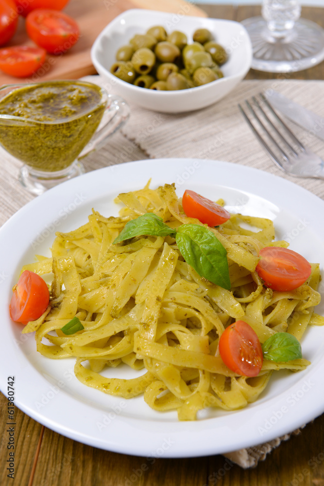 Delicious pasta with pesto on plate on table close-up