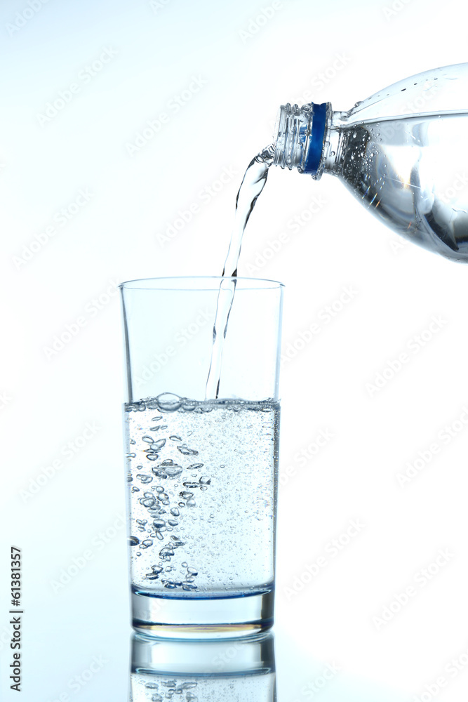 Pour water from bottle into  glass, on light blue background