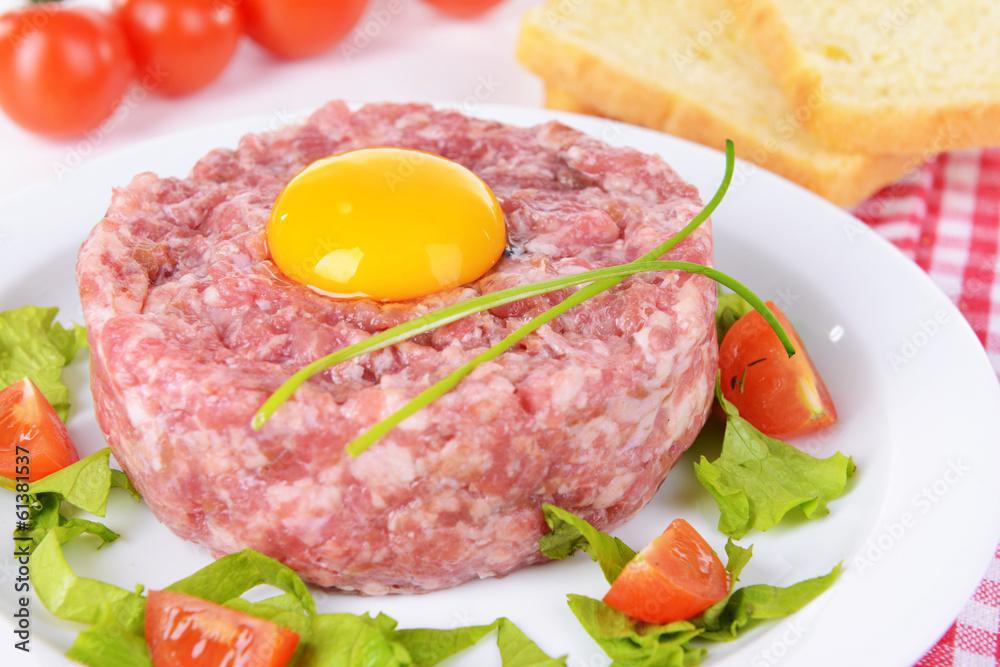 Delicious steak tartare with yolk on plate on table close-up