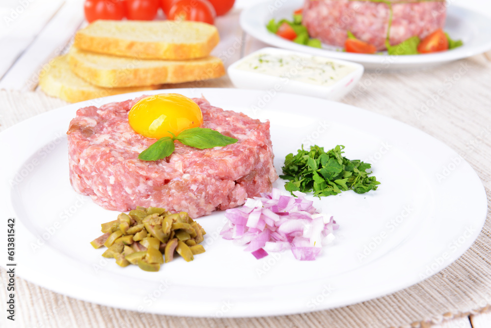 Delicious steak tartare with yolk on plate on table close-up