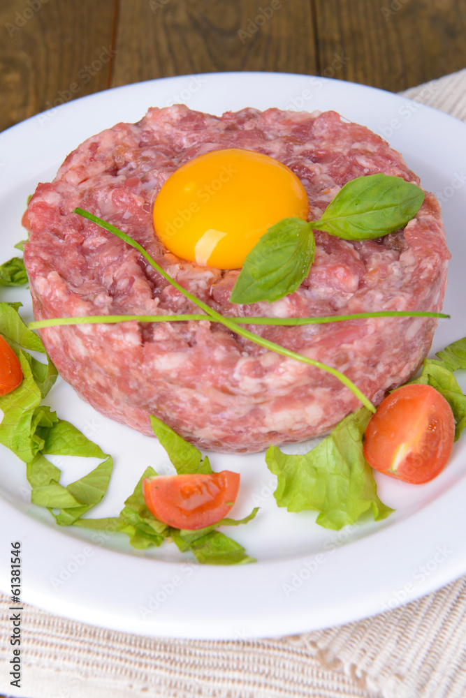 Delicious steak tartare with yolk on plate on table close-up
