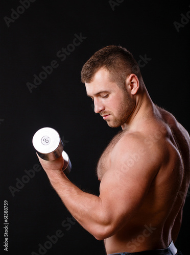 Fit muscular man exercising with dumbbell
