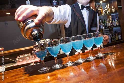 Barman pouring blue coloured drinks to the glasses on the bar co
