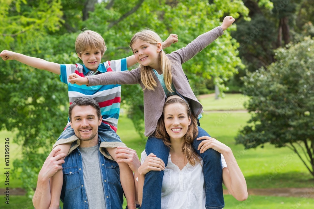 Fototapeta premium Happy parents carrying kids on shoulders at park