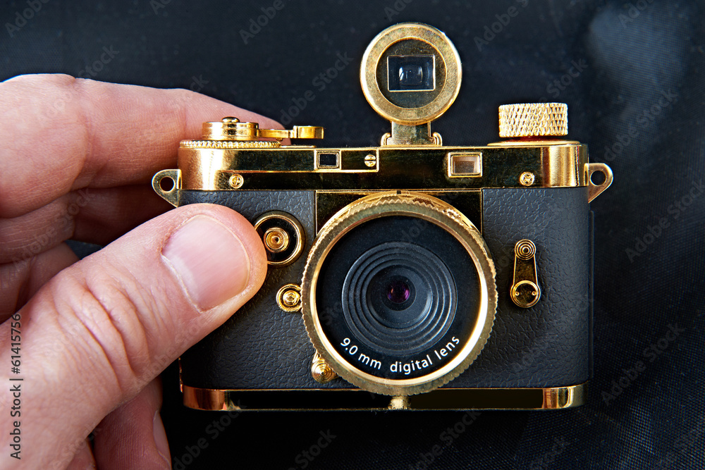Mini gift golden camera in big hand Stock Photo | Adobe Stock