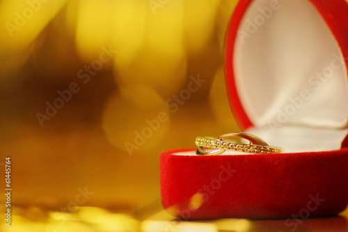 złoty pierścionek w czerwonym pudełku na złotym tle