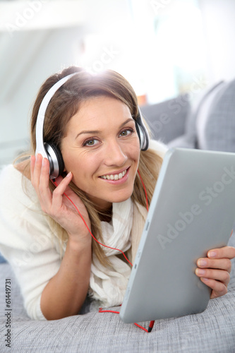 Smiling woman listening to music with tablet and headphones