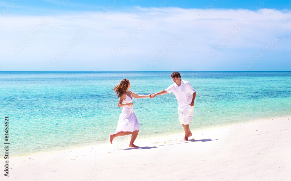 Young beautiful couple dancing on the beach of a tropical paradi