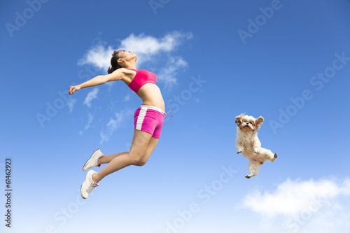Foto young woman and dog jumping in the sky