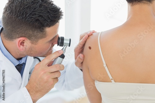 Doctor examining mole on back of woman photo