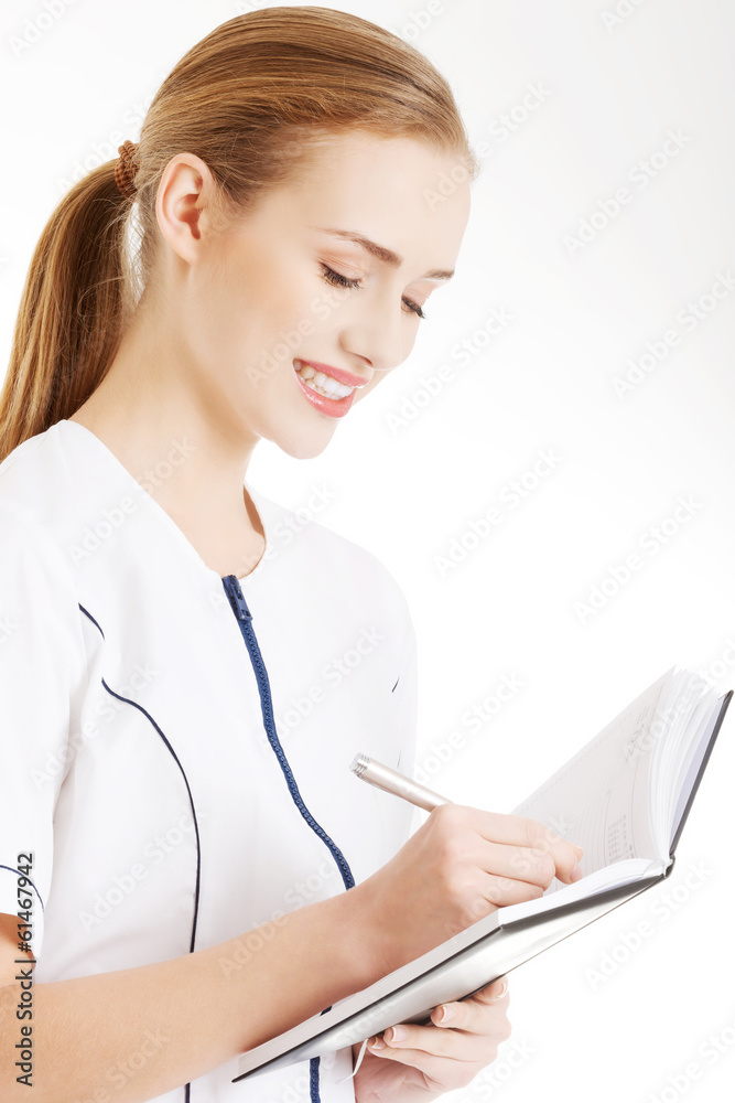Beautiful caucasian doctor or nurse is writing in notebook. Beautiful caucasian doctor or nurse is writing in notebook.