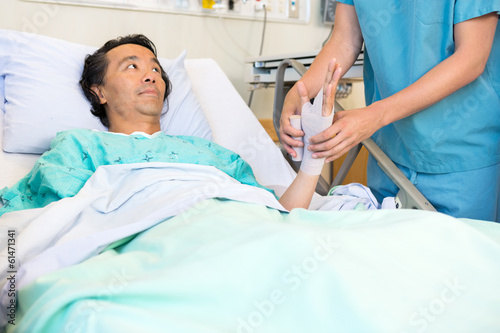 Patient Looking At Nurse Putting Bandage On Hand