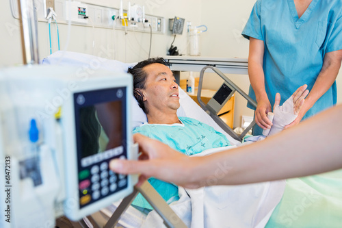 Nurse Putting Bandage On Patient's Hand While Coworker Operating
