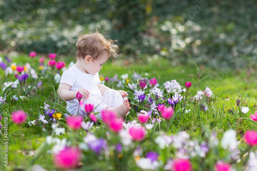 Sweet baby girl playing in a field of flowers
