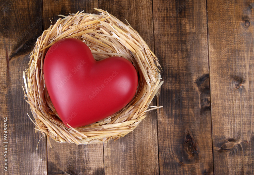 Decorative heart in nest, on wooden background Decorative heart in nest, on wooden background