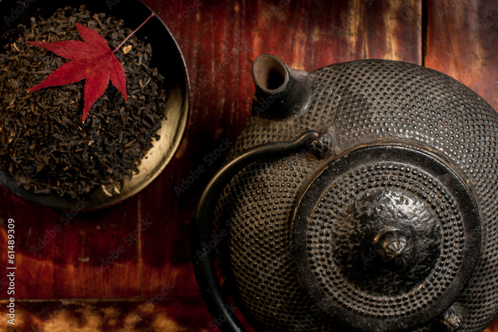 Fototapeta premium Japanese iron teapot and heap of tea leaves from top.