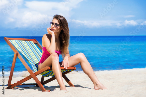 A young woman in a swimsuit relaxing on a deckchair on the beach