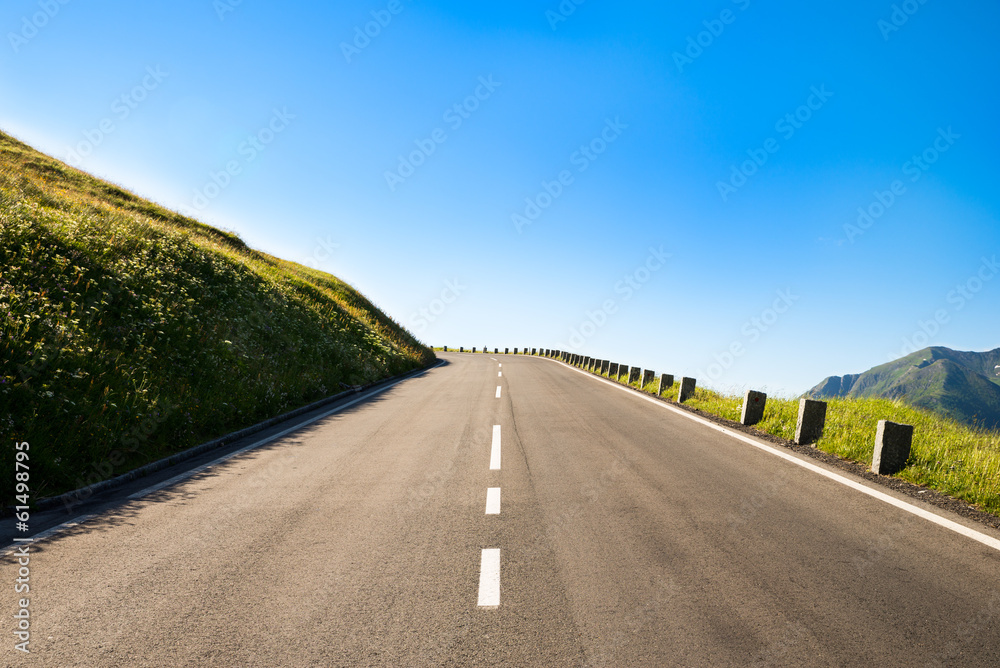 Obraz premium empty country road with a sharp left curve in the brow of a hill