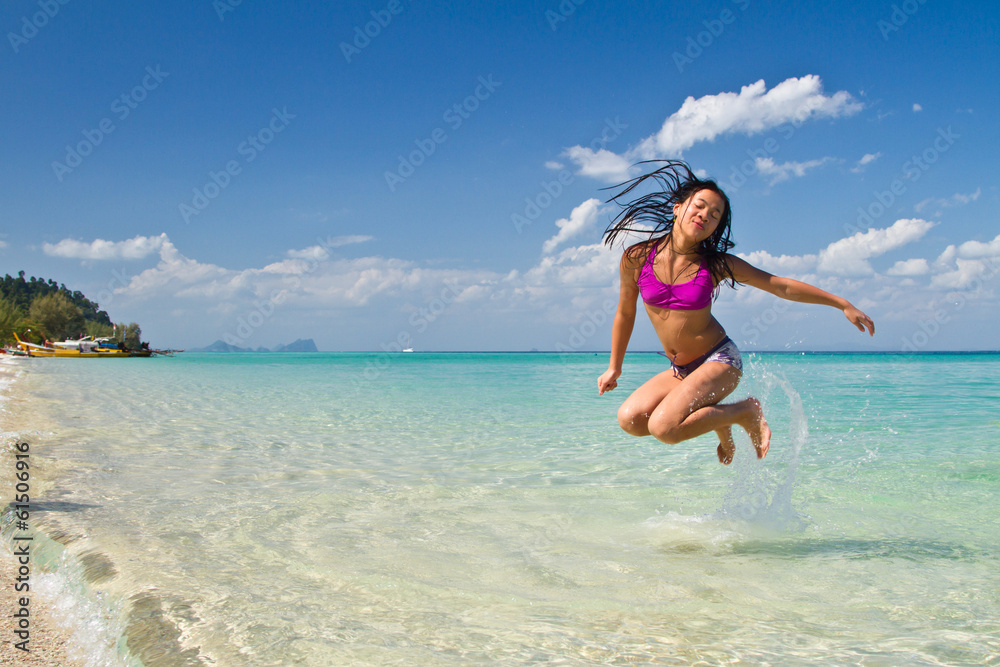 Girl jumping in the water at the beach of the Koh Ngai island Th