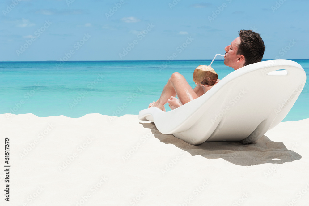 Man lie on lounger with coconut. Leisure activity on beach.  Man