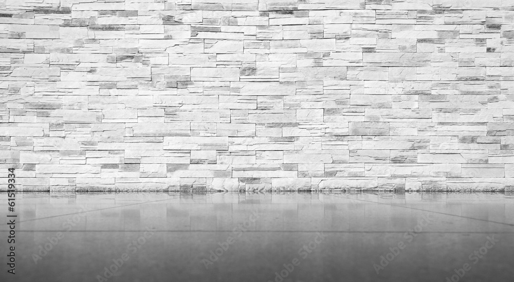 Fototapeta premium A textured white stacked stone wall is paired with a smooth, reflective dark grey concrete floor in this monochrome architectural background.