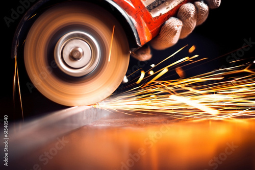 Worker cutting metal with grinder. Sparks while grinding iron