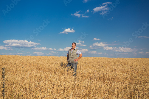 Happy smiling caucasian old farmer standing in wheat fields