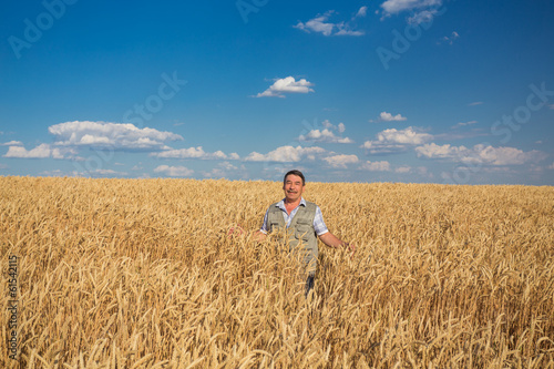 Happy smiling caucasian old farmer standing in wheat fields