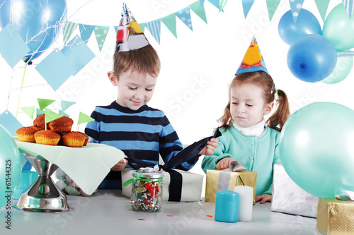 Two children at blue party table openning present