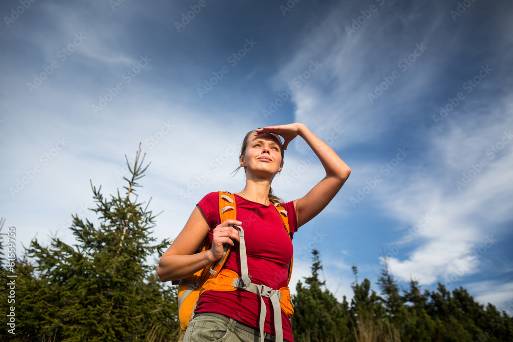 Obraz premium Pretty, female hiker going downhill in warm evening light