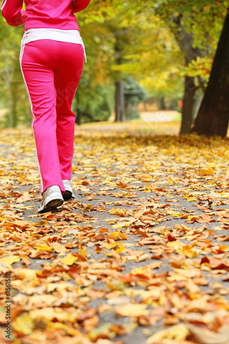 Woman running in autumn forest. Female runner training.