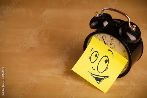 Post-it note with smiley face sticked on a clock