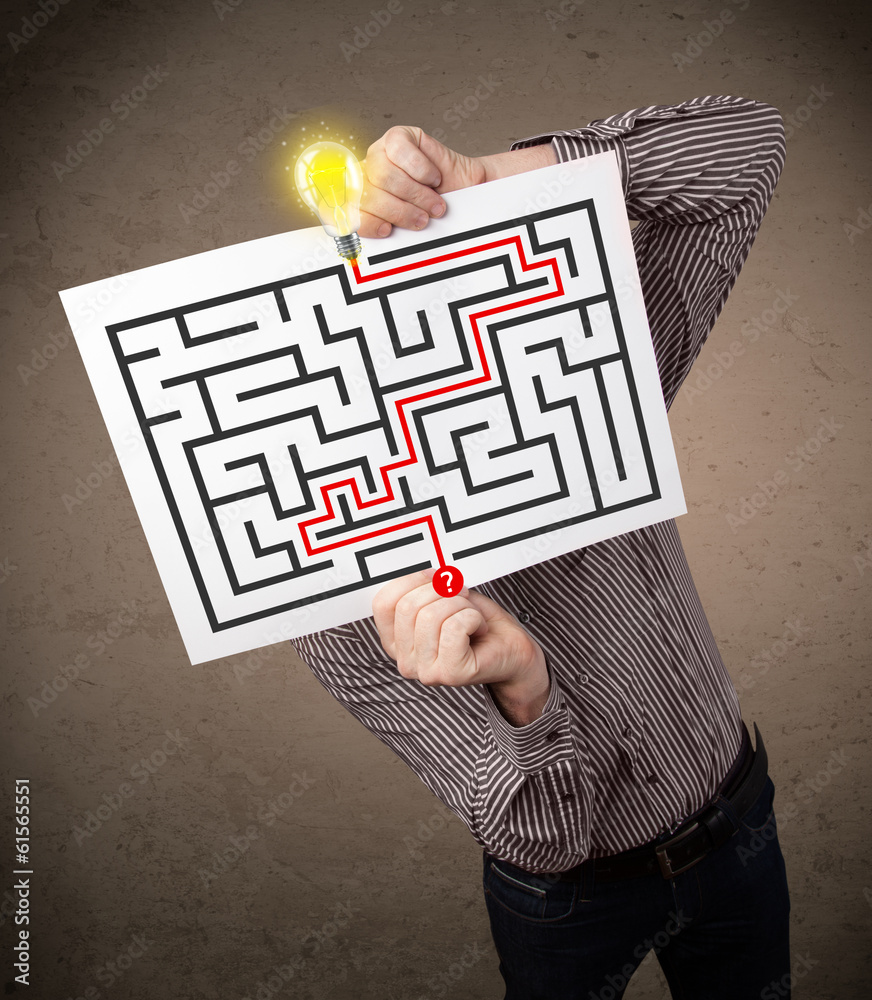 Businessman holding a paper with a labyrinth on it in front of h Businessman holding a paper with a labyrinth on it in front of h