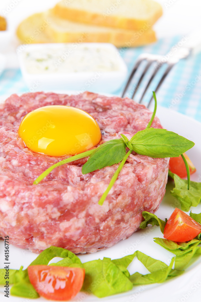 Delicious steak tartare with yolk on plate on table close-up Delicious steak tartare with yolk on plate on table close-up