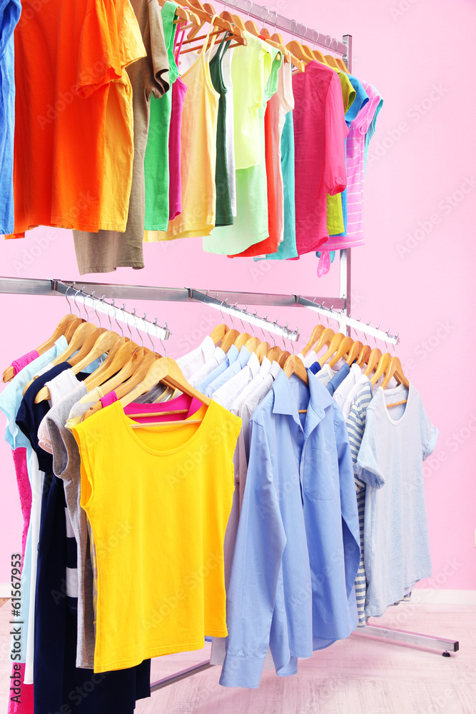 Fototapeta premium Different clothes on hangers, on pink background