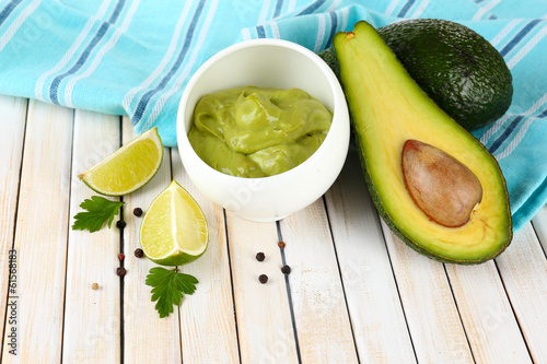 Fresh guacamole in bowl on wooden table