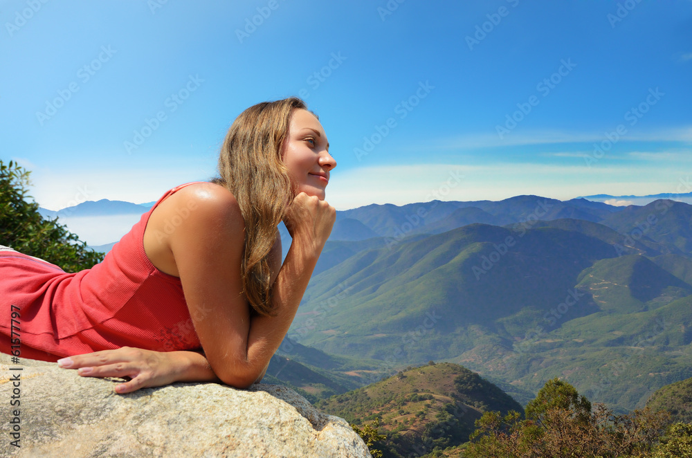 Young woman looking at the mountains on the edge of a cliff Young woman looking at the mountains on the edge of a cliff