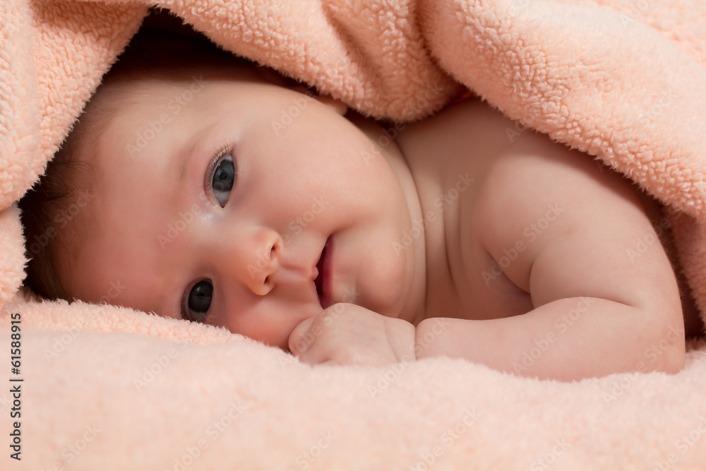 Baby girl is hiding under the peach-coloured blanket Baby girl is hiding under the peach-coloured blanket